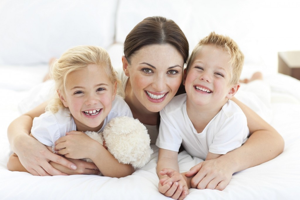 Happy mother and her children lying on a bed